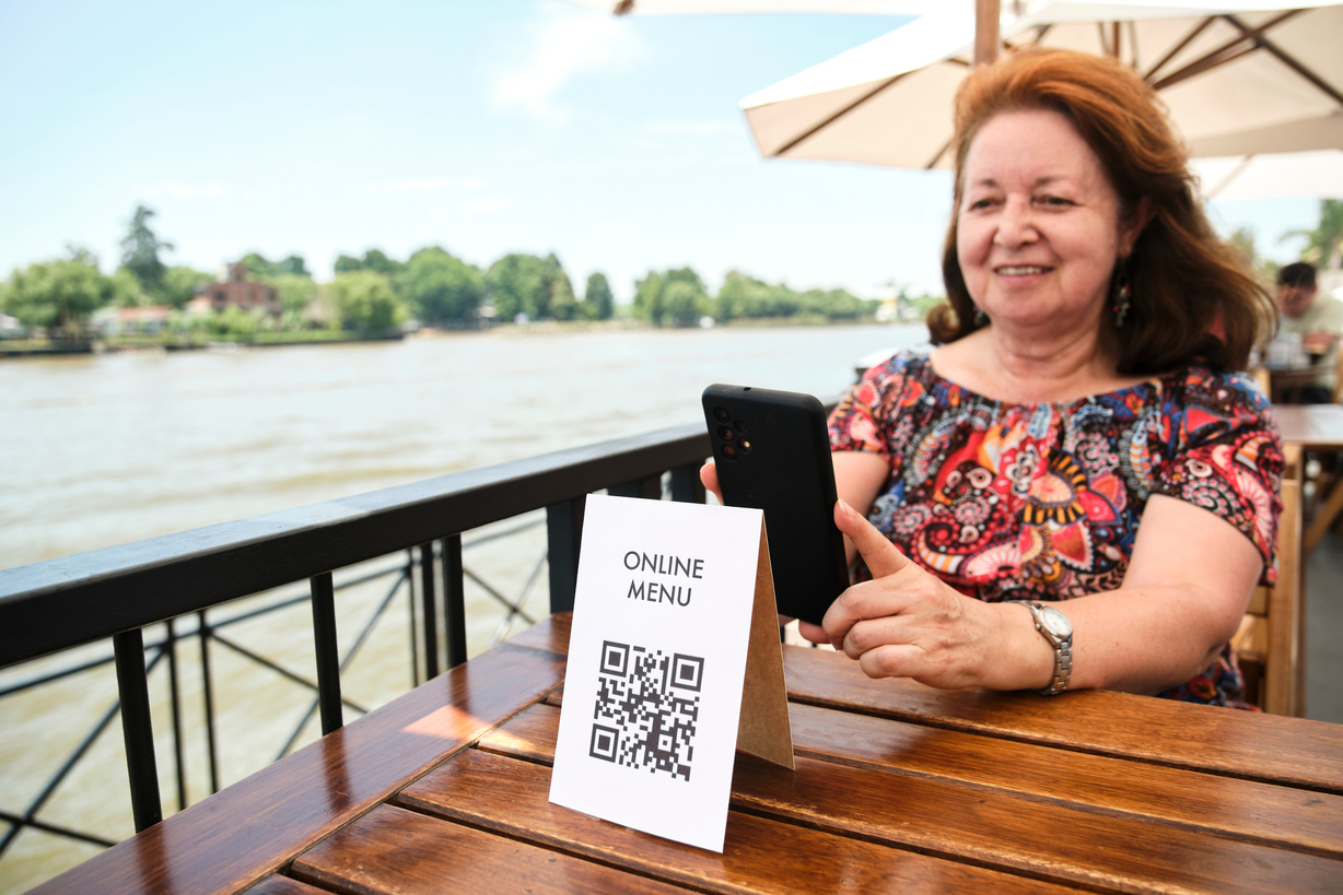 Mature Latin Woman Scanning a QR Code to Access a Restaurant Menu